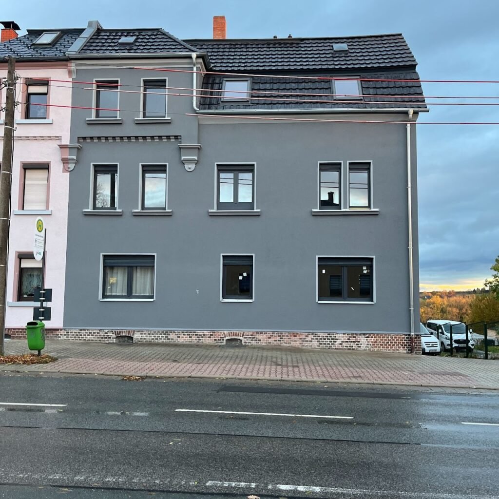 Frisch sanierte Hausfassade mit neuen Fenstern und modernem Anstrich