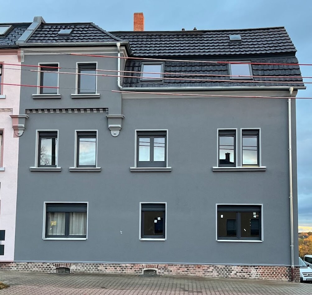Frisch sanierte Hausfassade mit neuen Fenstern und modernem Anstrich